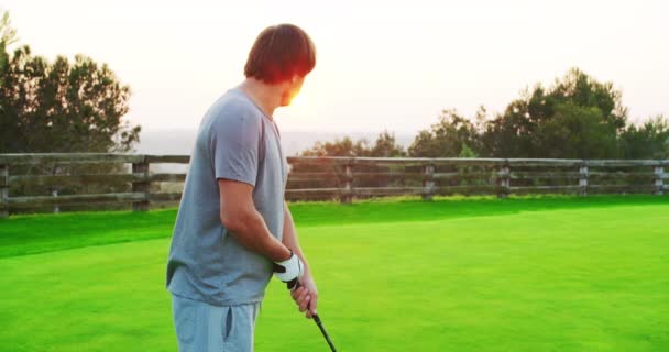 Homem golfista chuta uma bola enquanto joga em um campo de golfe . — Vídeo de Stock