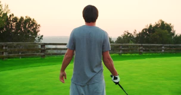 Caucasian golf player holding a club looking into the distance behind a flying ball. Golf field. — Stockvideo