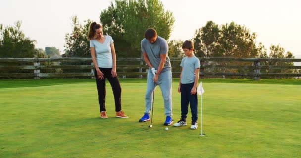Boldog szülők kisfiúval élvezik az időt együtt gyakorló golf klub. — Stock videók