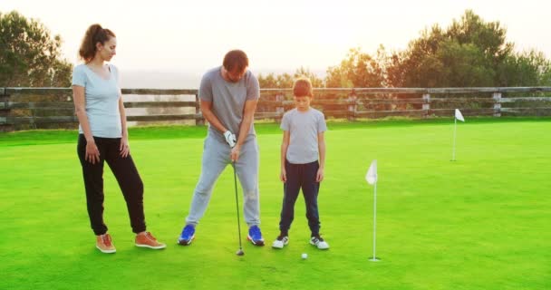 幼い息子と一緒にゴルフクラブで練習を楽しむ幸せな両親. — ストック動画