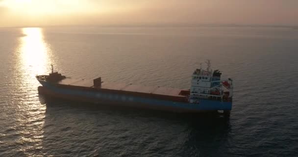 Flygfoto. En vacker solnedgång vid havet. Stort lastfartyg som flyter i havet. — Stockvideo