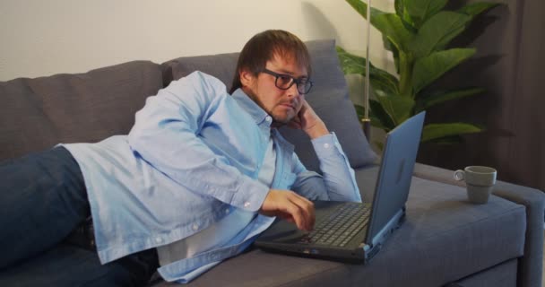Przystojny facet ciężko pracujący przy komputerze odkłada okulary i masuje oczy. Pracownik biurowy, wolny strzelec. Pracoholikiem. Zbliżenie. — Wideo stockowe