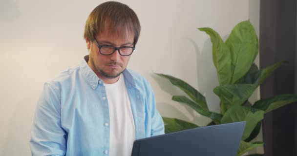 Businessman in eyeglasses with laptop computer drinking coffee or tea at office. Business, people and technology concept. — Stock Video