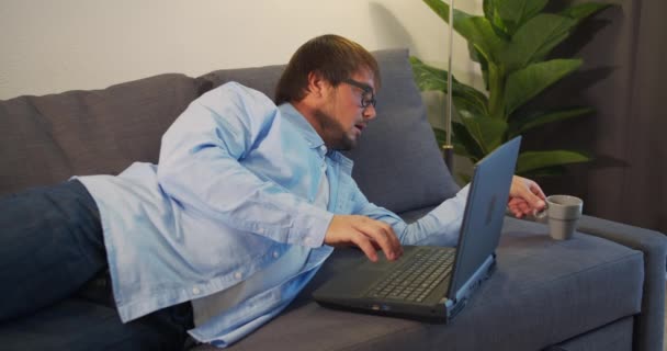 Businessman in eyeglasses with laptop computer drinking coffee or tea at office. Business, people and technology concept. — Stock Video