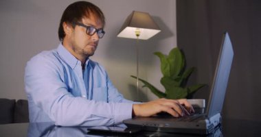 Evden internet üzerinden çalışan bir adam dizüstü bilgisayar kullanıyor.