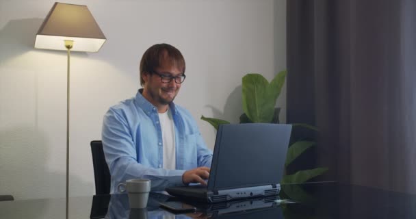 Smiling Man freelancer χρησιμοποιώντας φορητό υπολογιστή που εργάζονται από το σπίτι στο διαδίκτυο. — Αρχείο Βίντεο