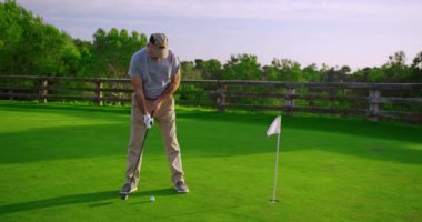 Yakışıklı yaşlı golfçü golf sopasını sallıyor, cennette golf oynuyor..