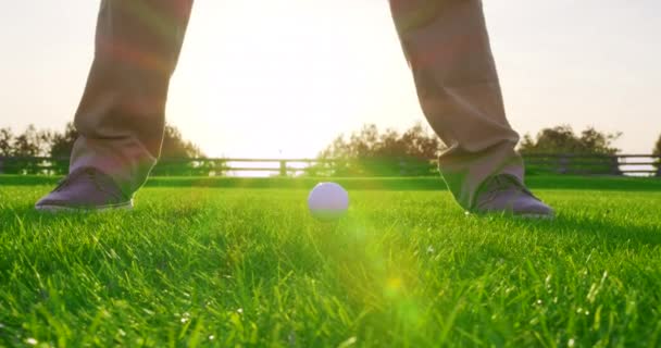 Volwassen man slaat een golfbal op tee met zonsondergang. Sluitingsdatum. — Stockvideo