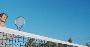 Erkek sporcu dışarıda sert kortta tenis oynuyor. Mutlu adam başarıyı kutluyor ve kazanıyor..