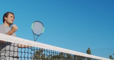 Erkek sporcu dışarıda sert kortta tenis oynuyor. Mutlu adam başarıyı kutluyor ve kazanıyor..
