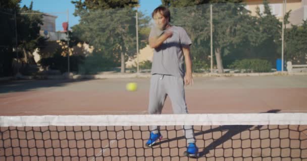 Profesionální tenista bít na míček s tenisovou raketou na jílovém kurtu. — Stock video