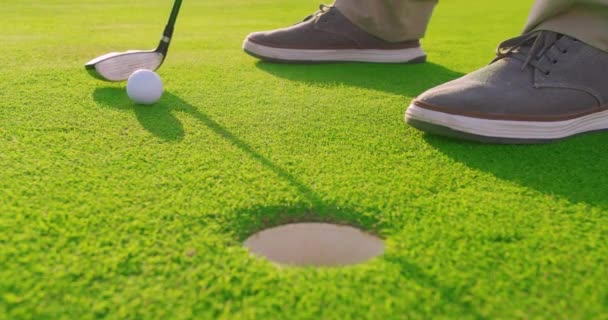 Homem adulto batendo uma bola de golfe no tee com pôr do sol. Fechar. . — Vídeo de Stock