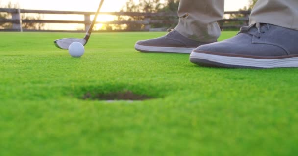 Homem adulto batendo uma bola de golfe no tee com pôr do sol. Fechar. . — Vídeo de Stock