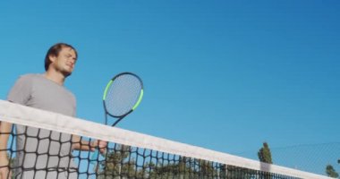 Mavi arka planda tenis maçından sonra el sıkışan oyuncular.