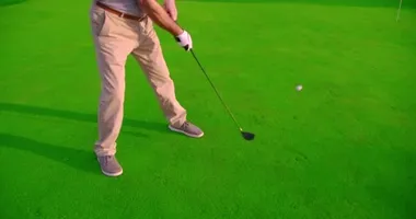 Yetişkin bir adam golf topuna gün batımıyla vuruyor. Yakın çekim..