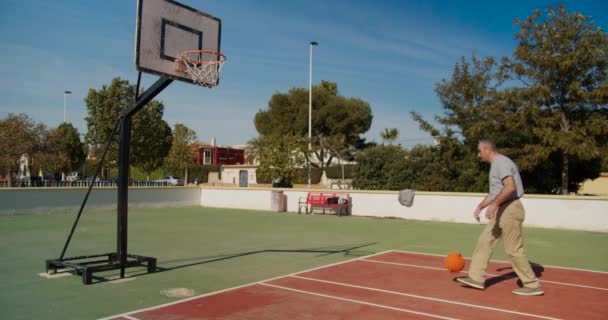 Starý muž hrát na basketbalovém hřišti. — Stock video