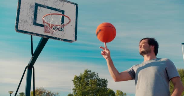 Basketballball balanciert und dreht sich auf einem Fingerspieler auf einem Outdoor-Basketballfeld. — Stockvideo