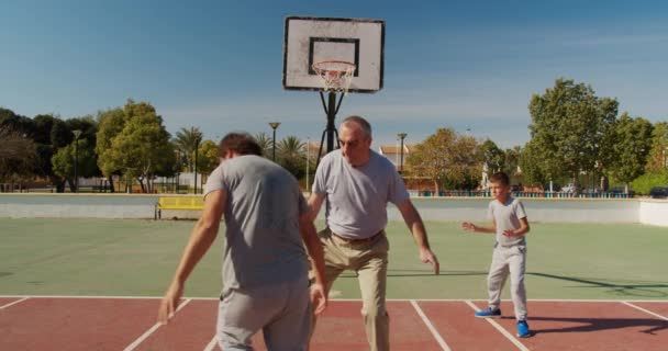 Famille multigénération jouant au basket sur un terrain extérieur . — Video