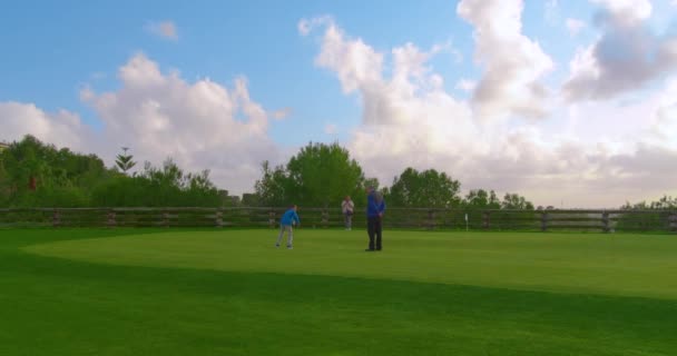 Dziadek z wnukami grającymi w golfa na idealnym polu golfowym. Ramy czasowe. — Wideo stockowe
