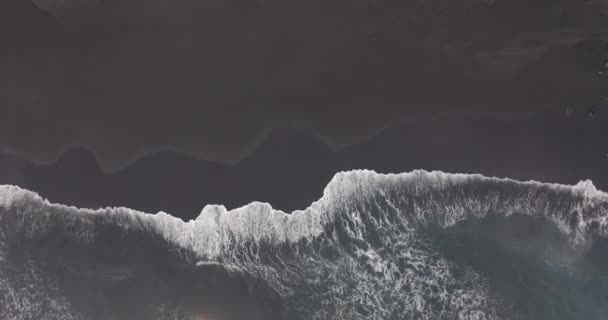 Vista aérea. Ondas quebrando contra praia de areia preta na Islândia . — Vídeo de Stock