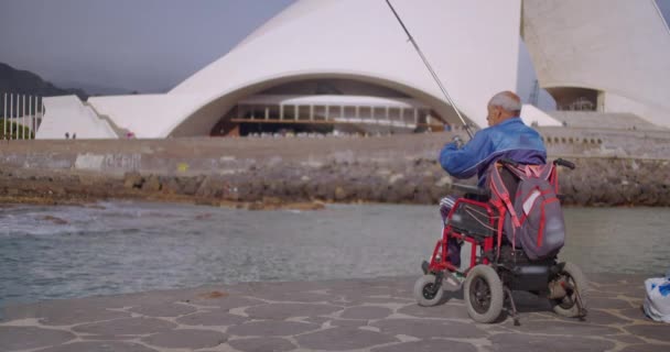 Eldelry niepełnosprawny rybak na wózku inwalidzkim połowów. — Wideo stockowe
