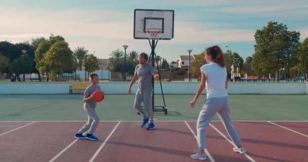 Rodina hraje basketbal na venkovním hřišti . — Stock video