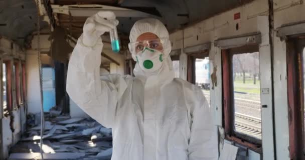 Female chemist with protective mask and white gloves displays tube with fluid sample positive. — Stock Video