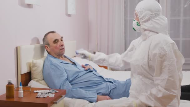 Bekämpning av koronavirusepidemi och akuta luftvägssjukdomar med pandemi. Temperaturmätning av en sjuk äldre man under en epidemi. — Stockvideo