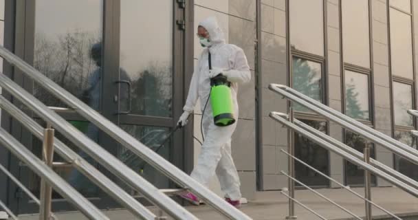 Εργαζόμενος με προστατευτική στολή απολυμαίνει επιφάνειες από τον ιό της στέψης. Αντιβακτηριακά υγειονομικά μέτρα σε καραντίνα. — Αρχείο Βίντεο