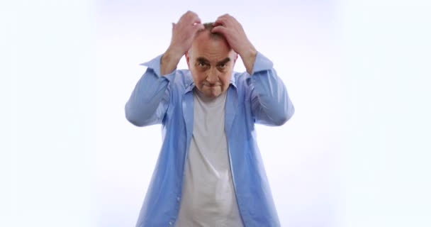 Öreg ember vakarózik a fejemhez, miközben fehér háttér. — Stock videók