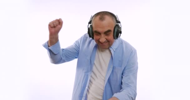 De oude man in een koptelefoon, luisterend naar muziek, dansend, glimlachend, vrolijk. Een zeer funky oudere opa dj. — Stockvideo