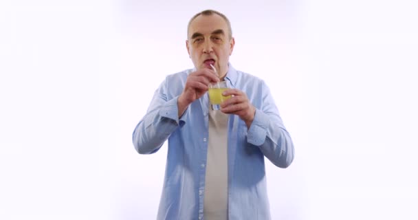 Porträtt av endera mannen dricker juice med ett sugrör och ler mot kameran. vit bakgrund. — Stockvideo