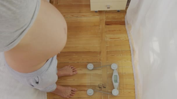 La femme enceinte debout sur des balances à la maison dans la chambre. Gros plan. 6k . — Video