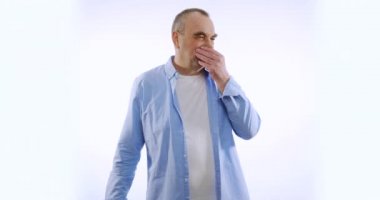 Yüzünde korkunç ifadeler olan, kötü kokan, beyaz arka planda izole olmuş burnu çimdikleyen olgun bir adamın portresi. Duyguların kavramı.