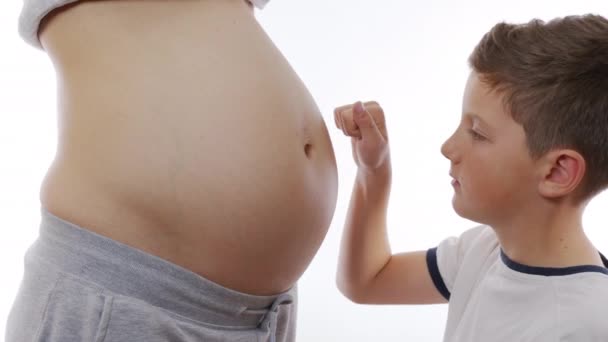 Chlapec objímá svou matku břichem. Dítě čeká na nového člena rodiny. — Stock video
