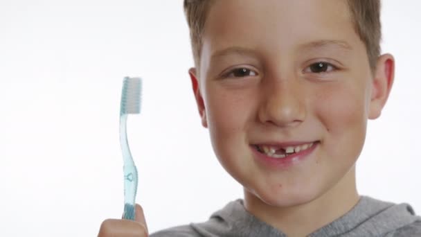 Крупним планом портрет щасливого усміхненого хлопчика, який тримає зубну щітку. Веселий хлопчик без переднього зуба . — стокове відео