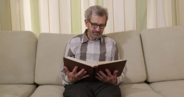 Emekli adam kitap okuyup kanepede otururken uyuyakalıyor..