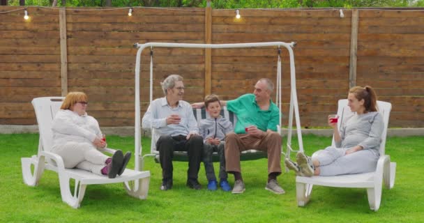 Celebración de la gran fiesta del jardín familiar. La gente está bebiendo, pasando platos, bromeando y divirtiéndose . — Vídeos de Stock