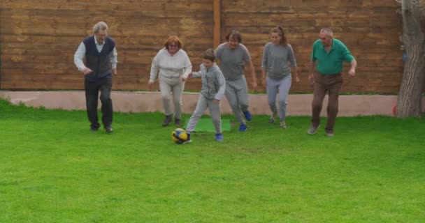 Wielopokoleniowa rodzina grająca razem w piłkę nożną w ogrodzie. — Wideo stockowe