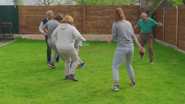 Flergenerationens familj spelar fotboll i trädgården tillsammans. — Stockvideo