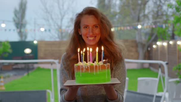 Jeune femme tenant un gâteau avec des bougies allumées . — Video