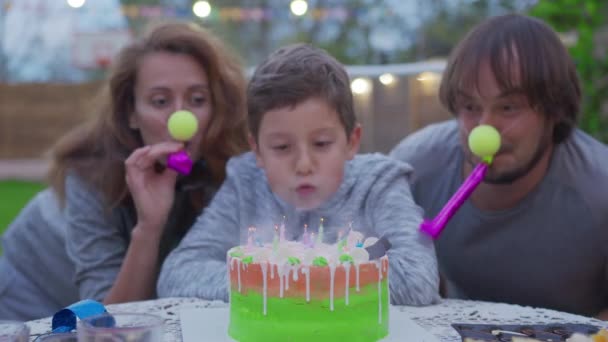 Joyeux petit garçon avec des parents soufflant des bougies d'anniversaire . — Video