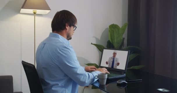 Il medico anziano indossa camice medico bianco, stetoscopio, auricolare fa videochiamate a distanza. Vecchio medico adulto parla con fotocamera consulenza paziente online in web chat. Concetto di telemedicina . — Video Stock