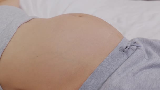 Закройте беременную женщину, играющую с ребенком, пинающимся изнутри утробы . — стоковое видео