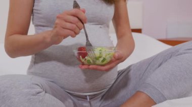 Çatallı hamile bir kadın sebze salatası yer, iyi beslenir. Hamile bir kadın doğmamış çocuk için faydalı bir sebze salatası yer. Uygun beslenme kavramı.