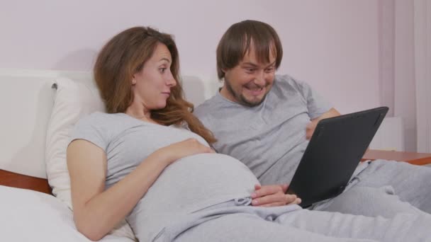 Happy rodina, mladý pár pomocí notebooku při pohledu na obrazovce počítače se těší sledování legrační sociální média videa dělá on-line nakupování relaxaci na pohovce doma spolu. — Stock video