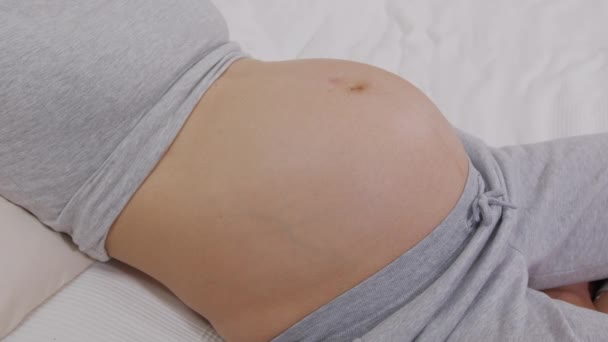 Cierre a la mujer embarazada jugando con el bebé pateando desde dentro del vientre.. — Vídeos de Stock