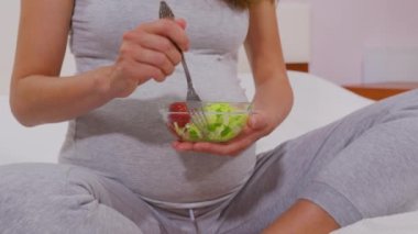 Çatallı hamile bir kadın sebze salatası yer, iyi beslenir. Hamile bir kadın doğmamış çocuk için faydalı bir sebze salatası yer. Uygun beslenme kavramı.