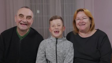 Mutlu dişsiz büyükbaba, büyükanne ve torun birlikte kameranın önünde gülüyorlar. Yakın çekim..