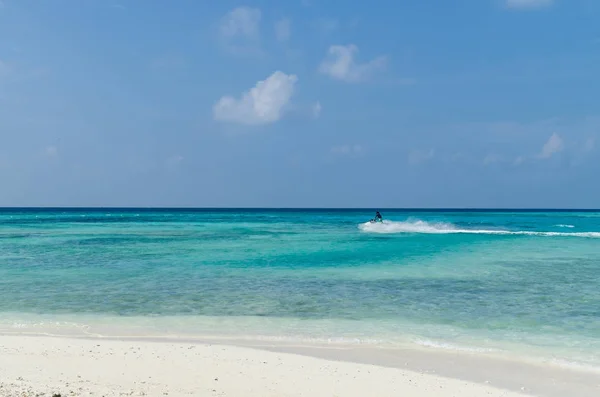 Maldiverna - November 2017: man ridande på en vattenskoter i Indiska oceanen, Maafushis strand. Semester destination — Stockfoto